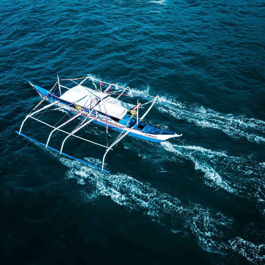 A wooden outrigger canoe floating on a turquoise reef off New Caledonia.